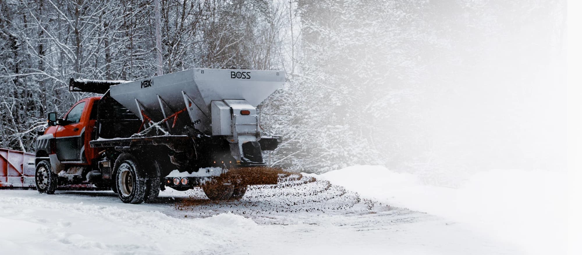 BOSS MBX hopper spreader spreading material from a flatbed truck